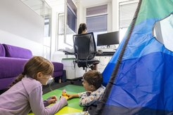 Frau arbeitet im Büro mit Kindern, die auf dem Boden spielen